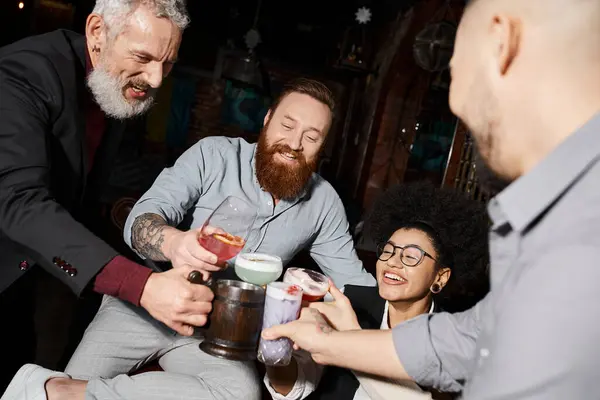 Bearded tattooed men and african american woman clinking glasses in cocktail bar, after work fun — Stock Photo