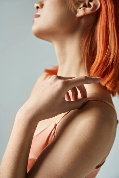 Feminine elegance, cropped view of young woman touching strap on slip dress on grey backdrop — Stock Photo