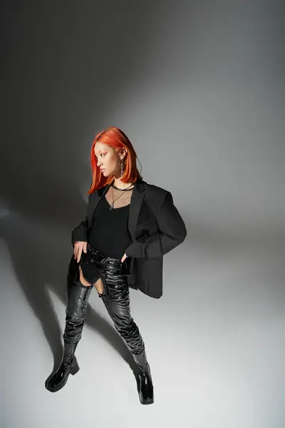 Stylish asian model with red hair posing with hand on hip, standing in latex boots and blazer — Stock Photo