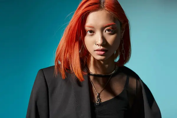 Young asian woman with red hair and nose piercing posing in oversized blazer on blue background — Stock Photo