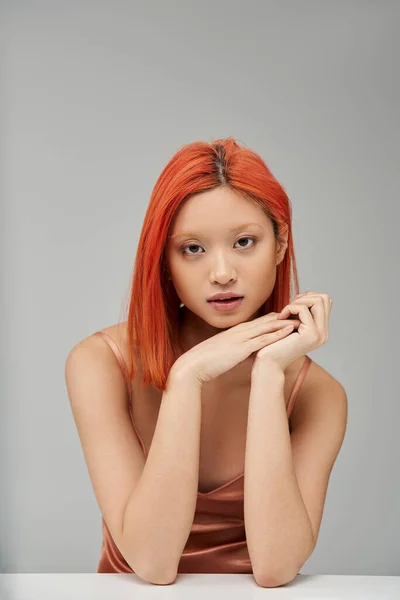 Bezaubernde junge Asiatin im pastellrosa Slip-Kleid, die in die Kamera auf grauem Hintergrund blickt — Stockfoto