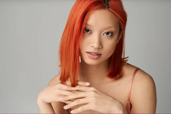 Porträt einer faszinierenden jungen Asiatin mit perfekter Haut, die vor grauem Hintergrund in die Kamera blickt — Stockfoto
