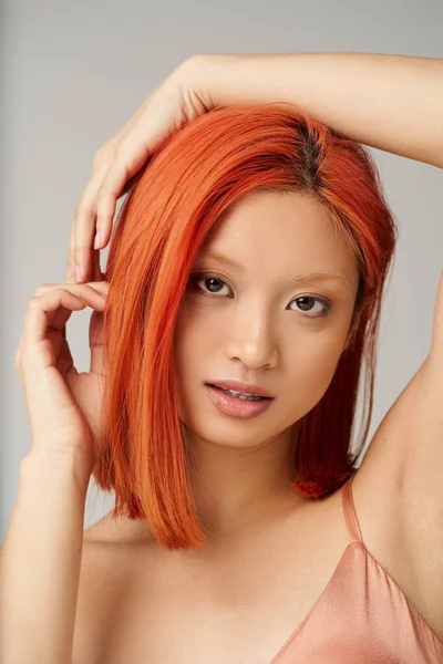 Séduisante jeune femme asiatique avec une peau parfaite posant sur fond gris, expression douce — Photo de stock