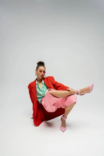 Comprimento total, modelo americano africano em traje moderno e salto alto rosa posando em pano de fundo cinza — Fotografia de Stock