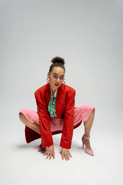 Индивидуальный стиль, африканская американка в современной одежде и розовые высокие каблуки позируют на сером фоне — стоковое фото