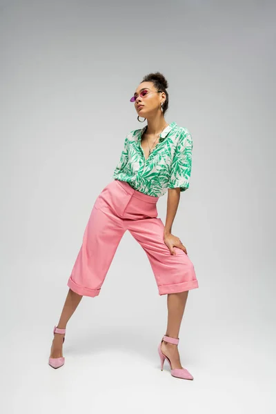 Comprimento total, modelo de moda americana africana em traje elegante e salto alto rosa no fundo cinza — Fotografia de Stock