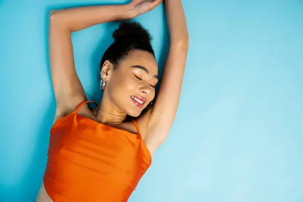 Cheerful african american woman in trendy wear lying on floor smiling sincerely with closed eyes — Stock Photo