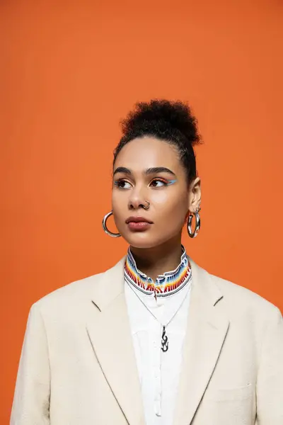 Porträt einer jungen hübschen afrikanisch-amerikanischen Frau mit trendigen Reifrohrringen auf orangefarbenem Hintergrund — Stockfoto