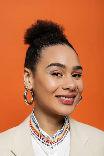 Portrait of cheerful african american model with bright make up and hoop earrings smiling at camera — Stock Photo