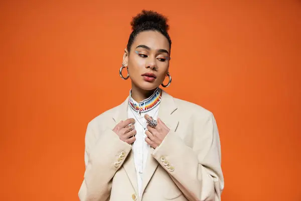 Beautiful african american model in beige blazer with accessories and vivid makeup looking away — Stock Photo