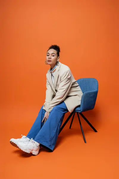 Schönes Mode-Modell in beige Blazer blaue Hose und hell auffallende Make-up sitzt auf blauem Stuhl — Stockfoto
