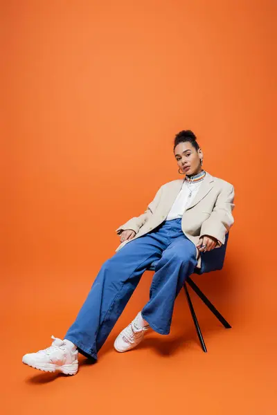 Belo modelo de moda afro-americano na rua vibrante roupa sentado relaxado na cadeira azul — Fotografia de Stock