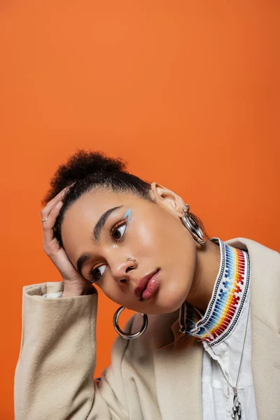 Retrato da mulher americana africana na moda com bun de maquiagem vibrante e acessórios olhando para longe — Fotografia de Stock