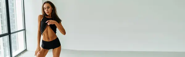 Donna sexy con capelli castani in posa in biancheria intima nera e canotta, mostrando pancia trafitta, banner — Foto stock
