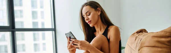 Pretty woman using smartphone and sitting on bean bag chair at home, social media influencer banner — Stock Photo
