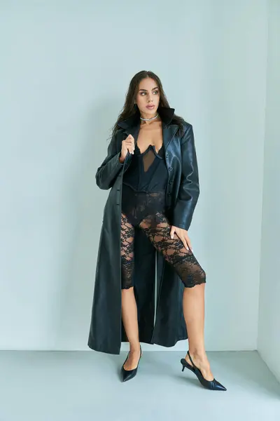 Pleine longueur, femme sexy aux cheveux mouillés posant en manteau en cuir noir et sous-vêtements en dentelle de gris — Photo de stock