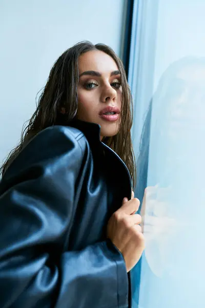 Mulher apaixonada com cabelo molhado morena posando em casaco de couro preto perto da janela, sedução — Fotografia de Stock
