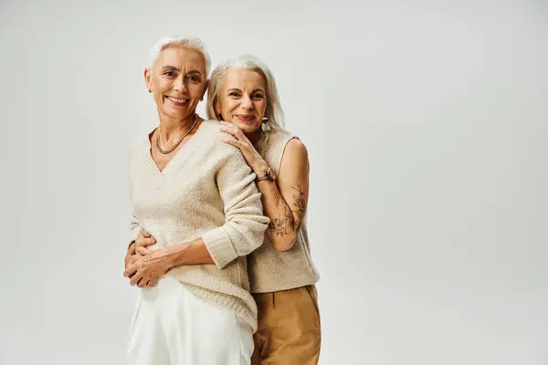 Joyeuses femmes âgées en tenue décontractée à la mode regardant la caméra sur gris, beauté intemporelle — Photo de stock
