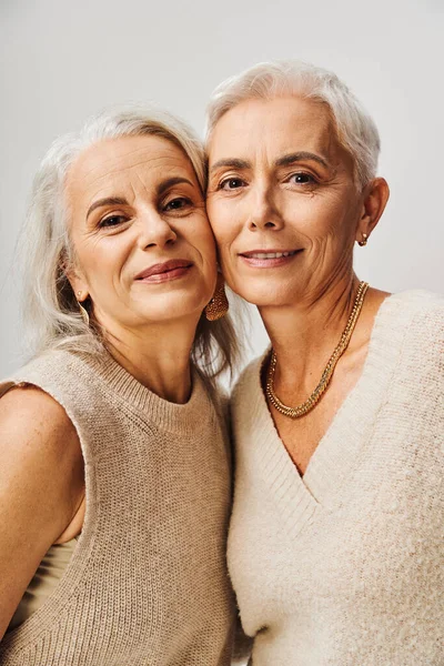 Ageless beauty, portrait of mature ladies with makeup and golden accessories on grey background — Stock Photo