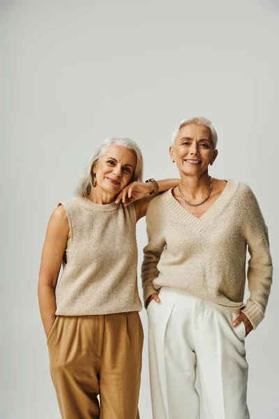 Smiley-Seniorinnen in stylischer Pastellkleidung blicken in die Kamera auf Grau, Positivität und Charme — Stockfoto