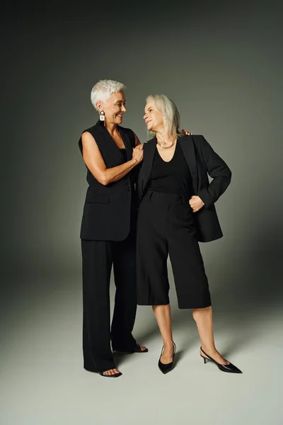 Glückliche Seniorinnen in schwarzer stylischer Kleidung, die sich über graues, trendiges Altern anlächeln — Stockfoto