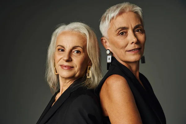 Ageless beauty, portrait of elegant senior models with silver hair looking at camera on grey — Stock Photo
