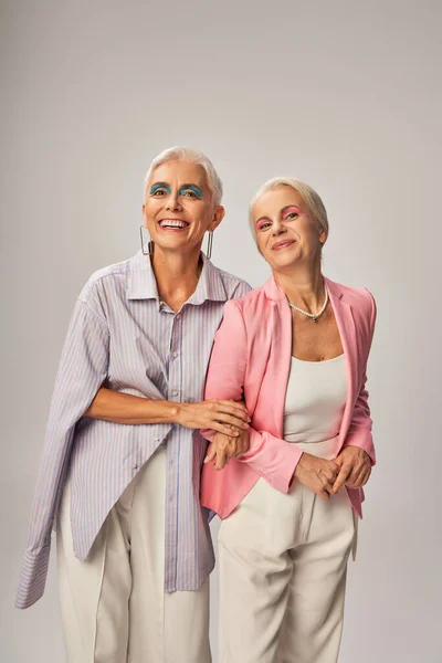 Positive senior female friends in stylish casual attire smiling on grey, happy and trendy aging — Stock Photo