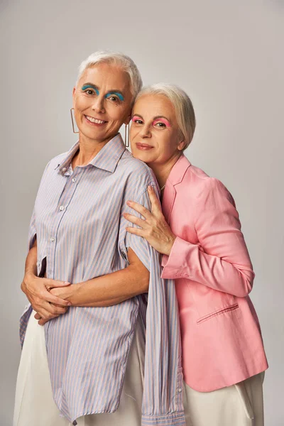Erfreut Senioren lebenslang Freunde in modischer Kleidung Blick in die Kamera auf grau, positive Alterung — Stockfoto