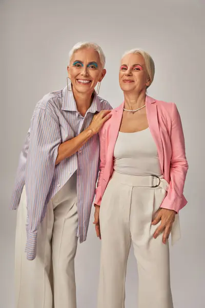 Cheerful senior ladies in fashionable casual attire smiling at camera on grey, happy aging — Stock Photo