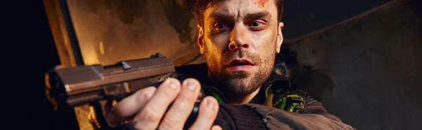 Personaje del juego centrado con la cara lesionada sin afeitar con el objetivo de pistola en el metro post-apocalíptico, pancarta - foto de stock