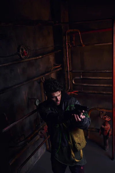 Высокий угол обзора концентрированного человека, нацеленного с оружием в опасном постапокалиптическом метро — стоковое фото