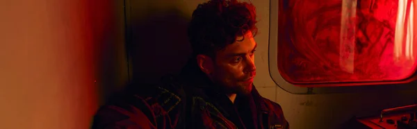 Безнадійний чоловік у покинутій кареті метро з червоним світлом і брудним вікном, пост-апокаліпсис, банер — стокове фото