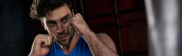 Resilient unshaven man exercising and boxing in darkness on urban street, banner — Stock Photo
