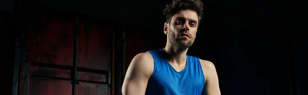 Ernsthafter athletischer Mann in Sportbekleidung sitzt auf der Sportbank und blickt in die Kamera in der dunklen Stadt, Banner — Stockfoto
