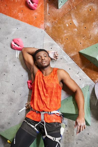 Vertical shot of african american man next to climbing wall with hand behind his head, bouldering — Stock Photo