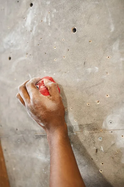 Обрезанный вид на руку спортивного африканского американца на валуне на скальной стене для скалолазания, спорт — стоковое фото