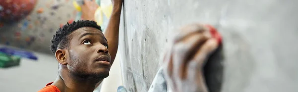 Sportliches afrikanisch-amerikanisches männliches Model klettert Boulderwand hoch und schaut auf, Sportler, Banner — Stockfoto