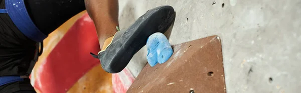 Vista ritagliata del piede di atletico giovane afroamericano sul masso sulla parete rocciosa rampicante, banner — Foto stock