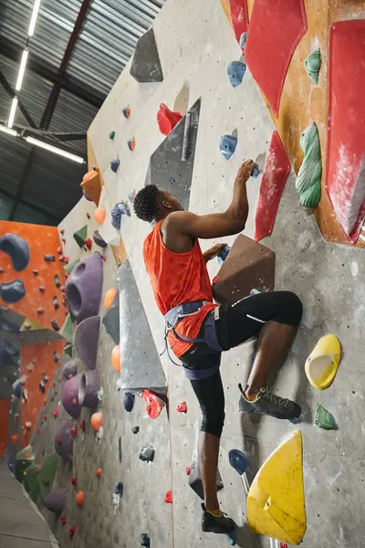 Good looking african american male model ascending up rock bouldering wall with alpine harness — Stock Photo