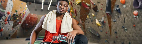 Athletic african american man on crash mat with towel on shoulders looking at camera, banner — Stock Photo