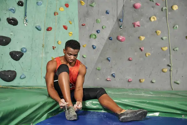 Handsome african american man sitting on crash pad and tying his shoes, bouldering concept — Stock Photo