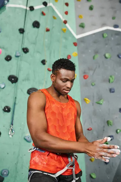 Vertical shot of muscular african american man using gym chalk with bouldering wall on backdrop — Stock Photo