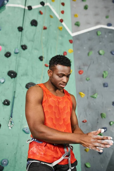 Vertical shot of muscular african american man using gym chalk with bouldering wall on backdrop — Stock Photo