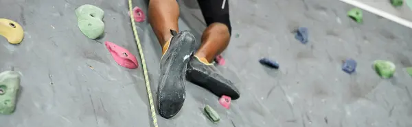 Cropped view of strong african american man climbing up bouldering wall with alpine harness, banner — Stock Photo
