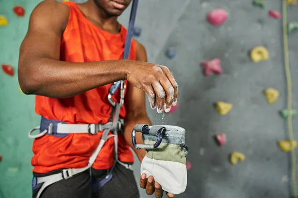 Обрезанный вид на африканского американца с помощью гимнастического мелом на его альпинистском снаряжении, боулдеринг — стоковое фото