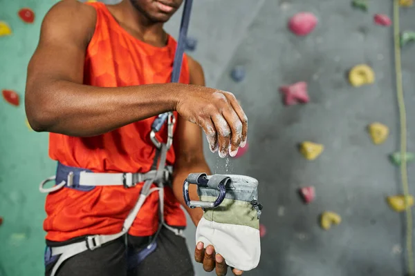 Ausgeschnittene Ansicht eines afrikanisch-amerikanischen Mannes mit Turnkreide auf seinem Klettergerät, Bouldern — Stockfoto