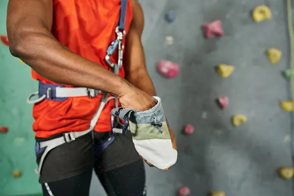 Cropped view of young african american man using gym chalk on his equipment before climbing up wall — Stock Photo