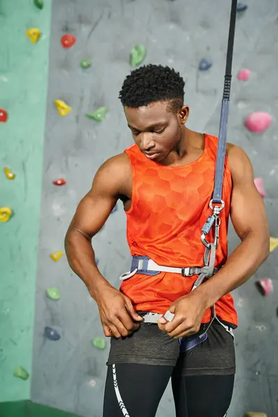 Handsome young african american man checking his safety rope before climbing up wall, bouldering — Stock Photo
