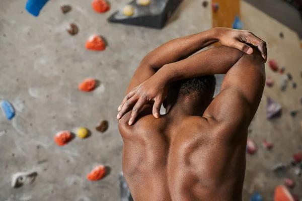 Вид ззаду на спортсменку підходить афроамериканський чоловік позує топлес з руками за його головою — стокове фото