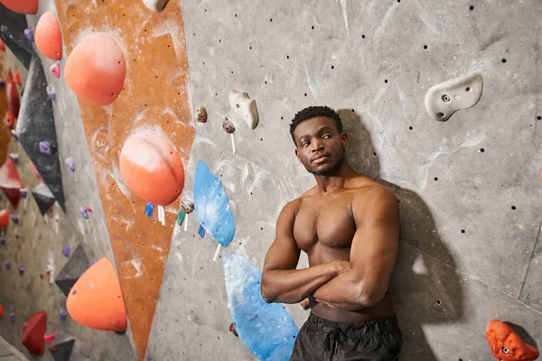 Homme afro-américain musclé posant seins nus avec les bras croisés sur la poitrine à côté du mur d'escalade — Photo de stock